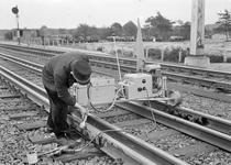 167341 Afbeelding van een wegwerker van de N.S. tijdens het bijslijpen van een raillas in de spoorlijn te Wezep.